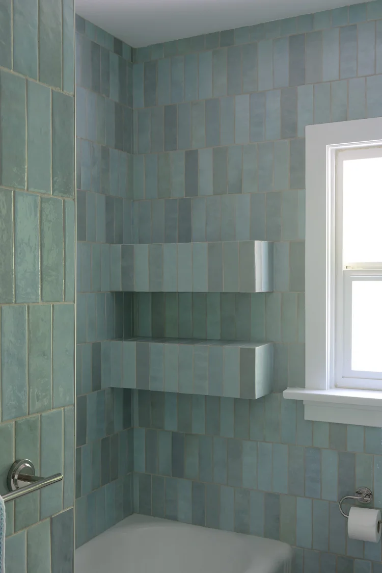 Modern two-story home with large glass windows, warmly lit interiors, and a balcony. Surrounded by trees and a manicured lawn at dusk. Cozy ambiance.