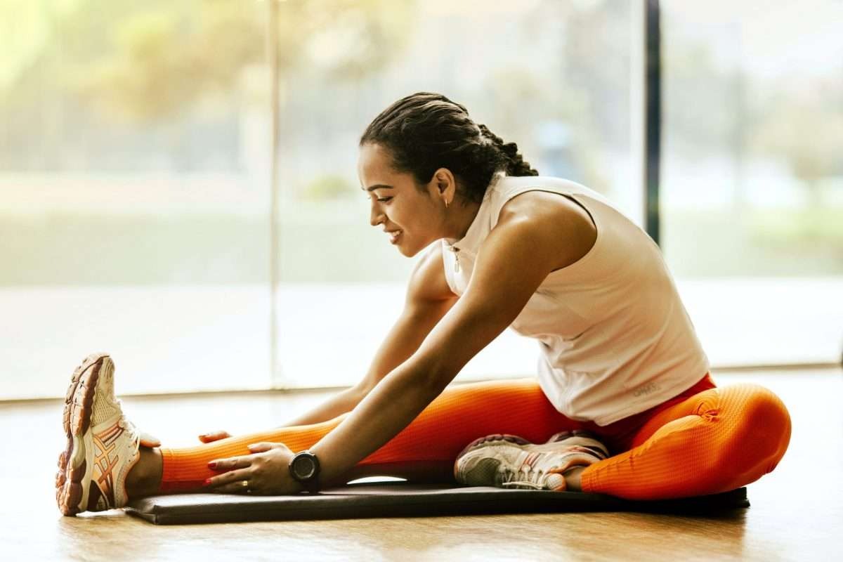 Woman stretching forward on a mat, wearing a fitness watch that can track resting heart rate