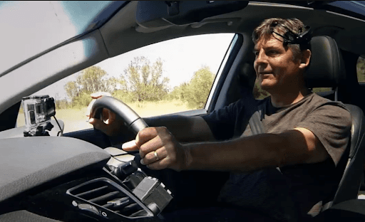 a man drives a car wearing an EMOTIV wireless EEG headset to help stay focused on road safety