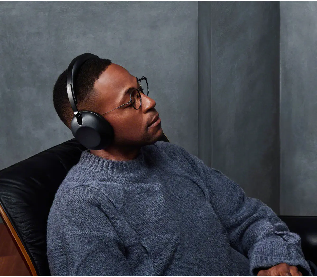 A wearing headphones sitting in a dark-colored chair