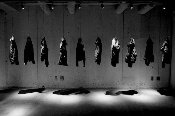 A silhouette of a person wearing sunglasses, with tousled hair, against a teal background.