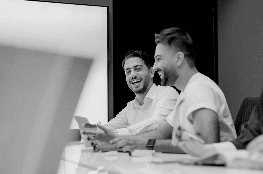 Two people at a desk a work smiling.
