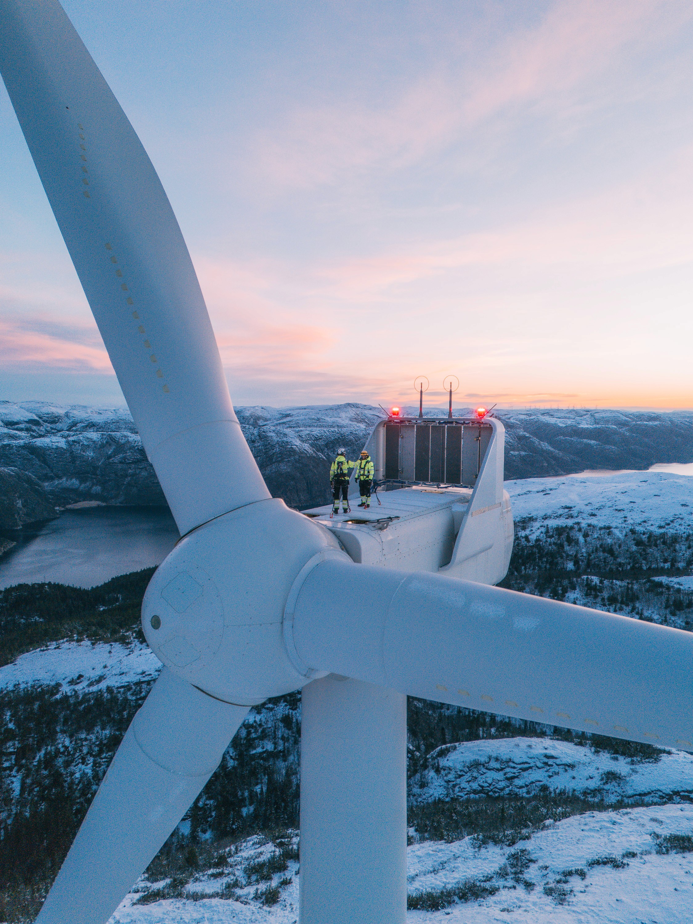 Vindteknikere på toppen av en vindturbin i solnedgang
