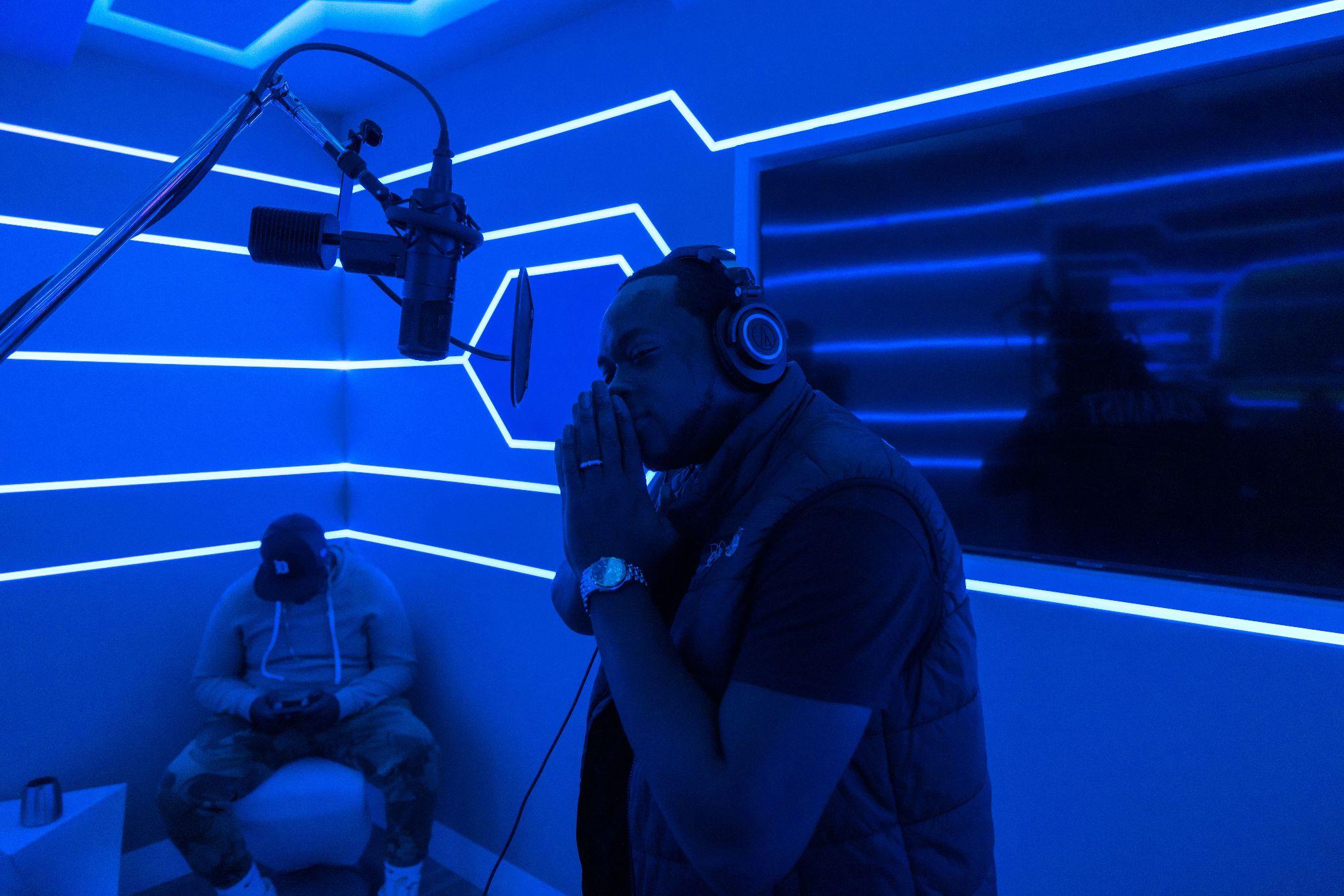 Rimanist performing at the microphone under blue stage lighting