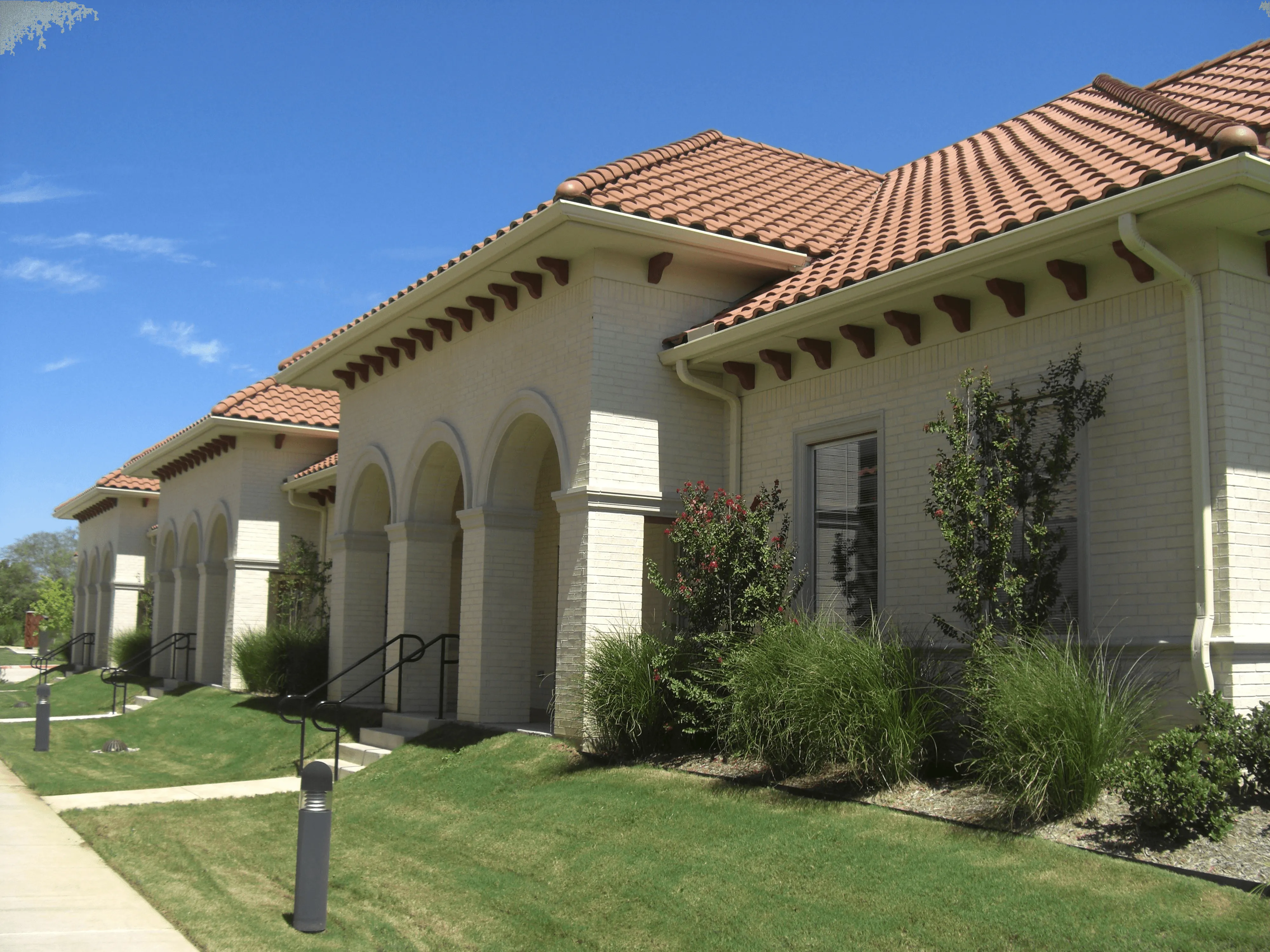 Mediterranean-style building with clay tile roof and arched entry.