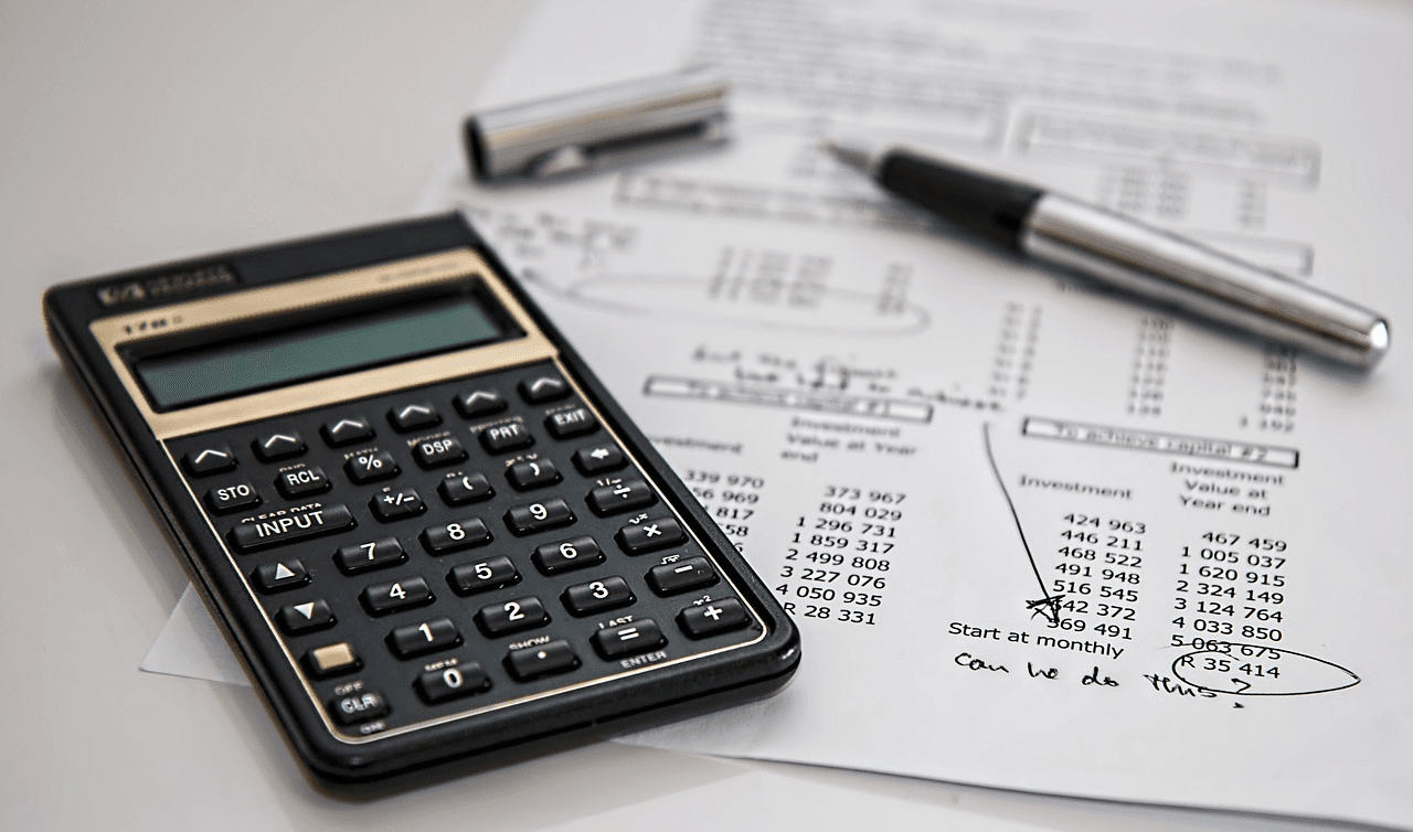 Calculator and pen on financial documents, representing tax filing for a USA LLC by non-US residents.