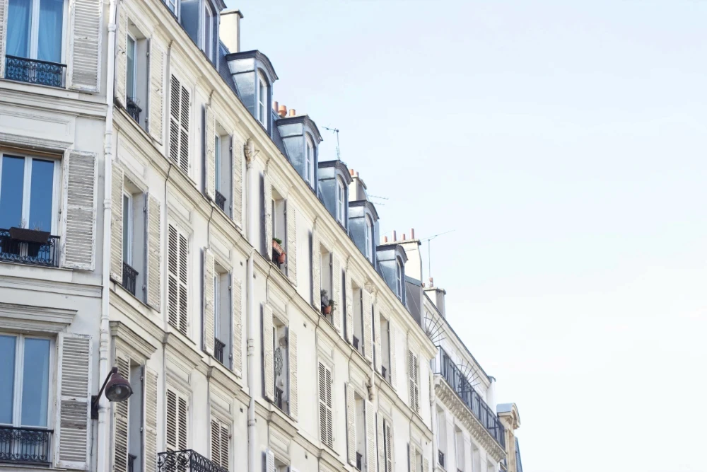 Classic white Parisian apartment building facade with mansard roof windows