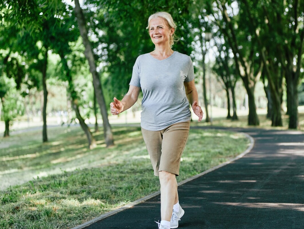 older woman exercising outside and enjoying the benefits of brisk walking and weight loss