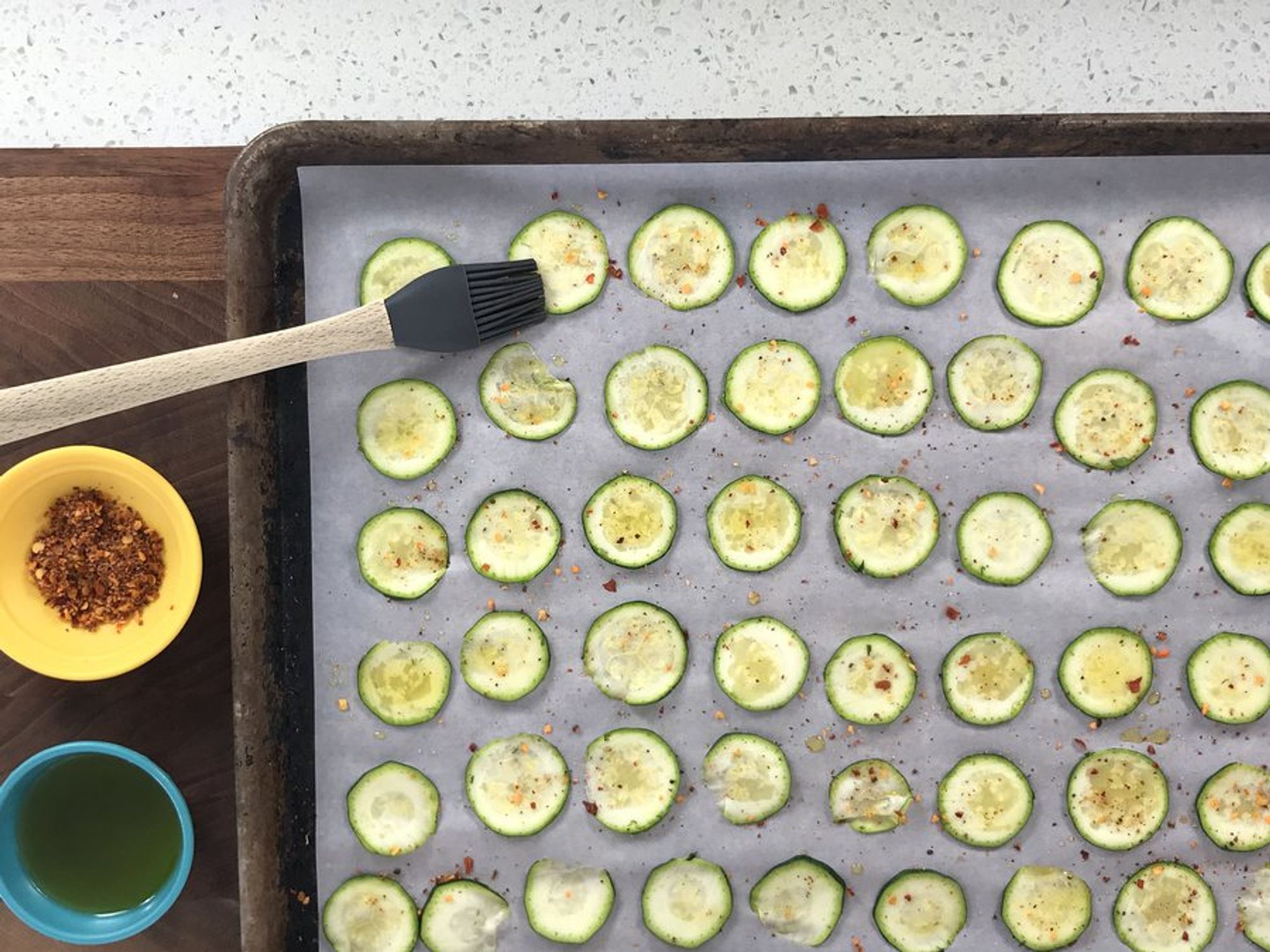 thinly sliced seasoned zucchini laid on a baking sheet
