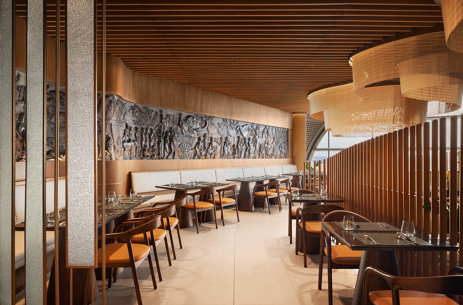 Dining corridor with an integrated bas-relief wall and timber finishes illustrating cultural continuity through architectural craft