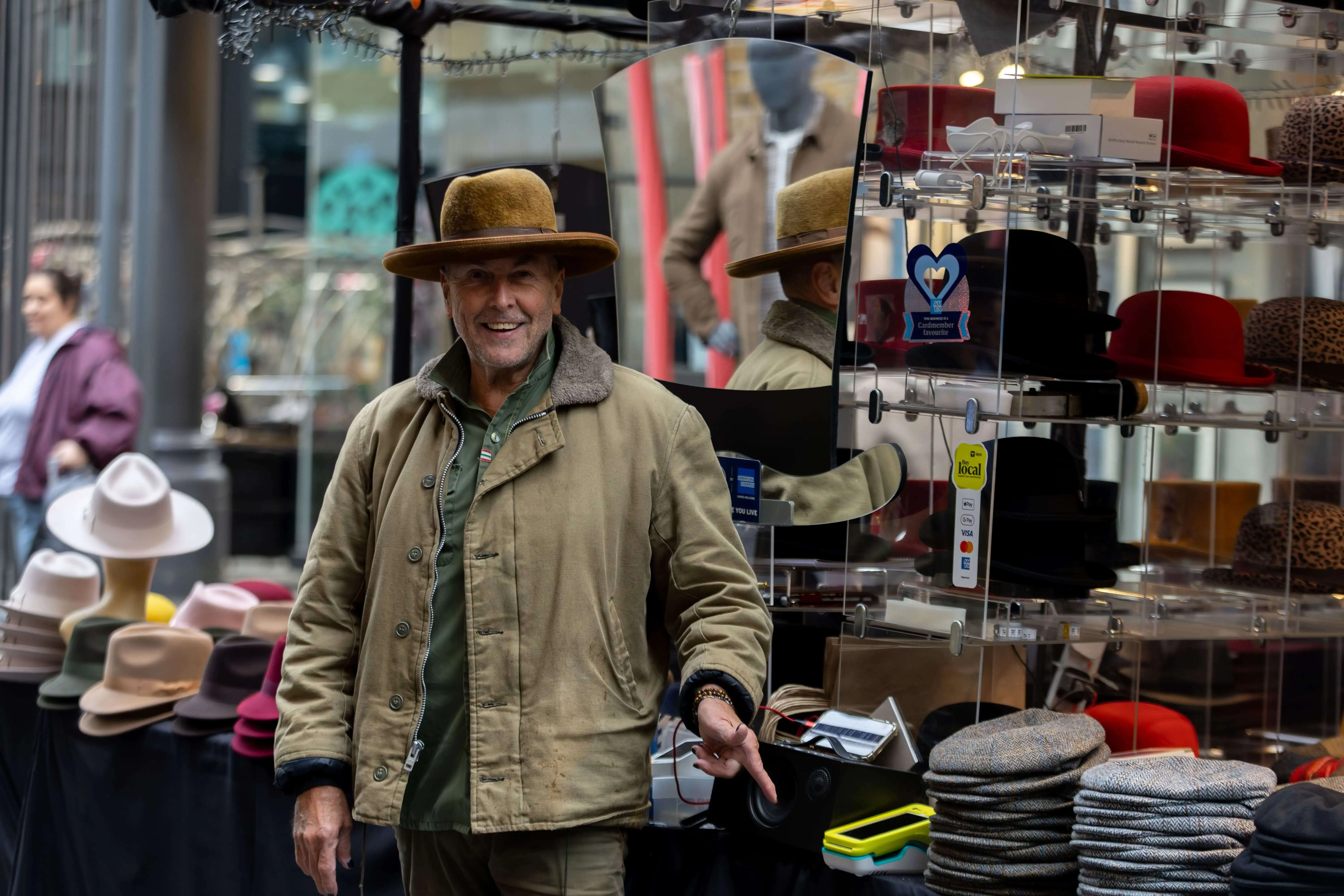 a local business owner points at a Teya card machine in his hat shop