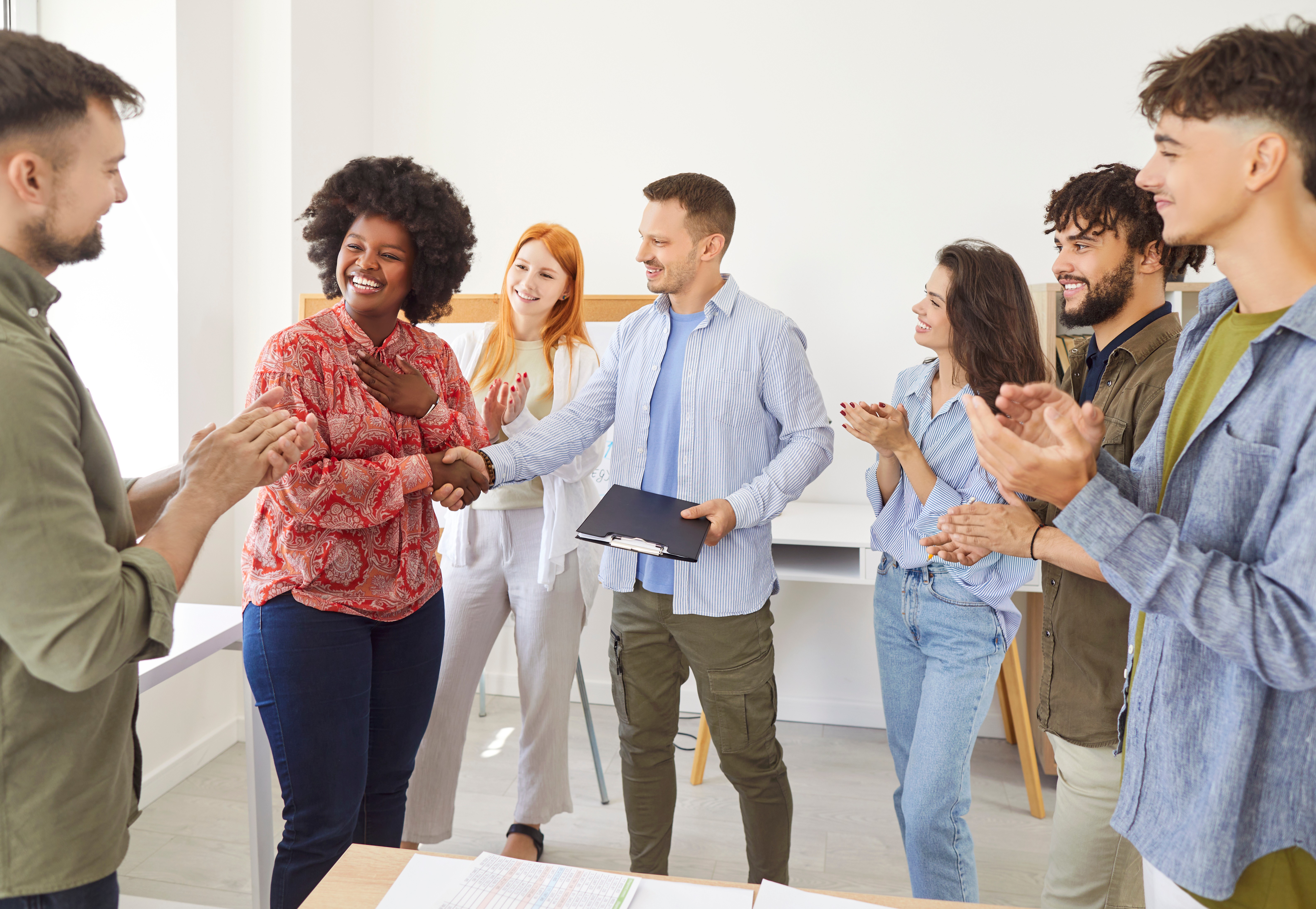 A diverse group of six people engaged in a lively discussion in a bright, modern office space.