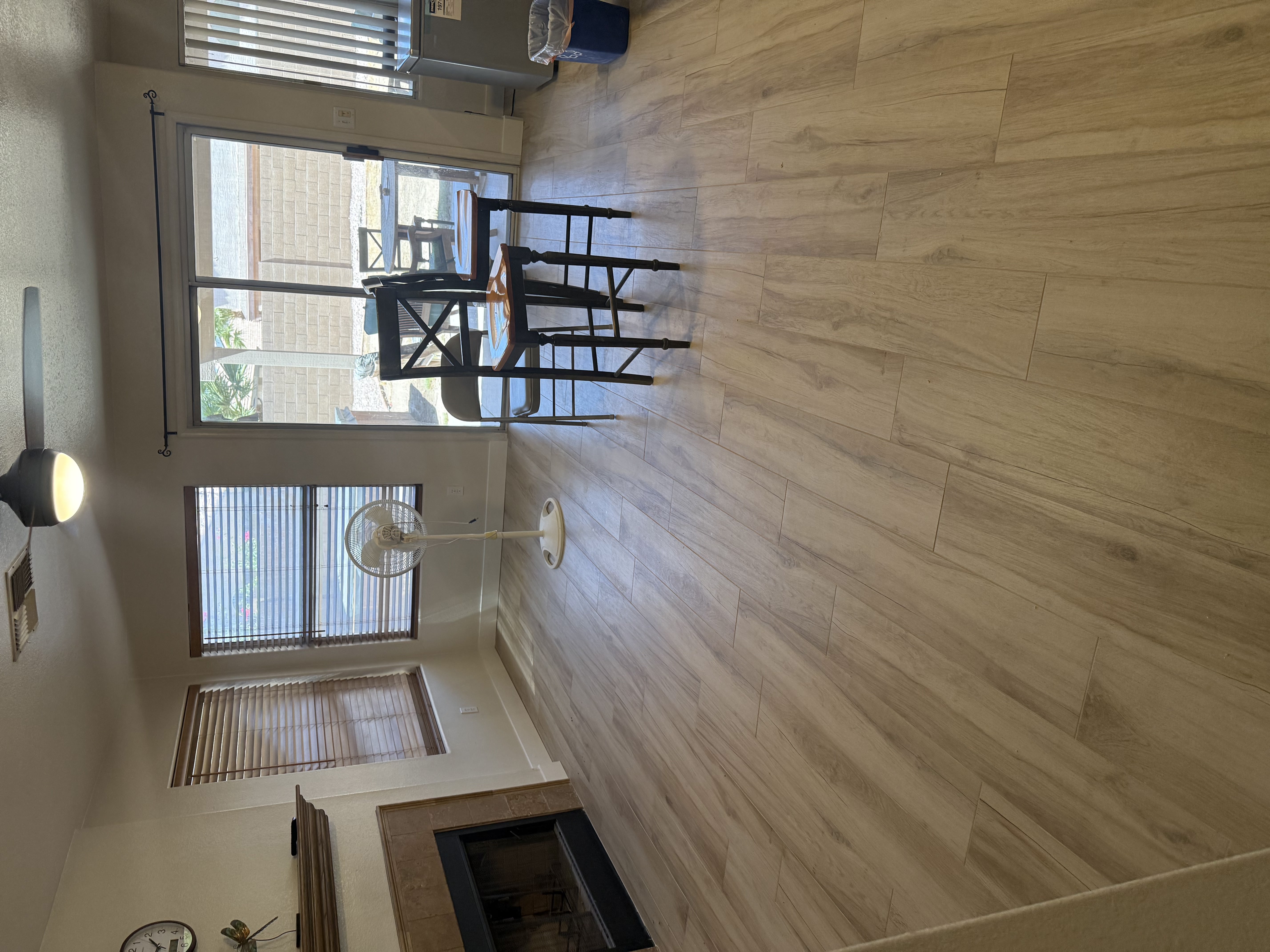 Modern living area with gray wood-look tile flooring, large sliding glass doors, and open space in a new home under construction.