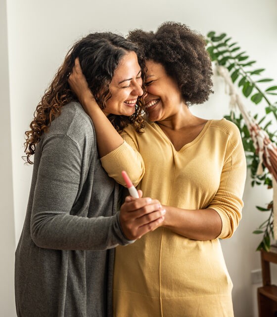 two women holding one another and smiling