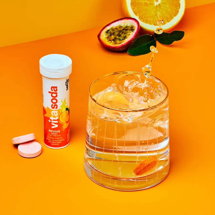 A Vita Soda Revive tube and two tablets beside a fizzing glass, with orange and passion fruit