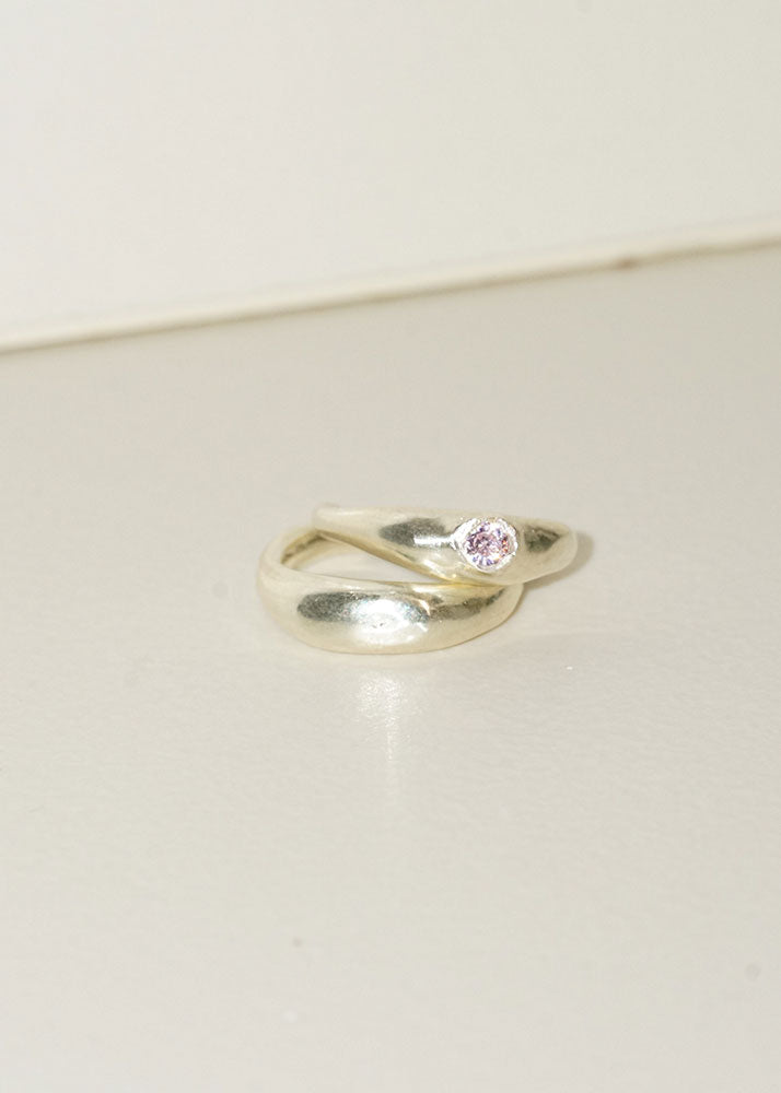 Silver ring with a pink gemstone on a light beige background