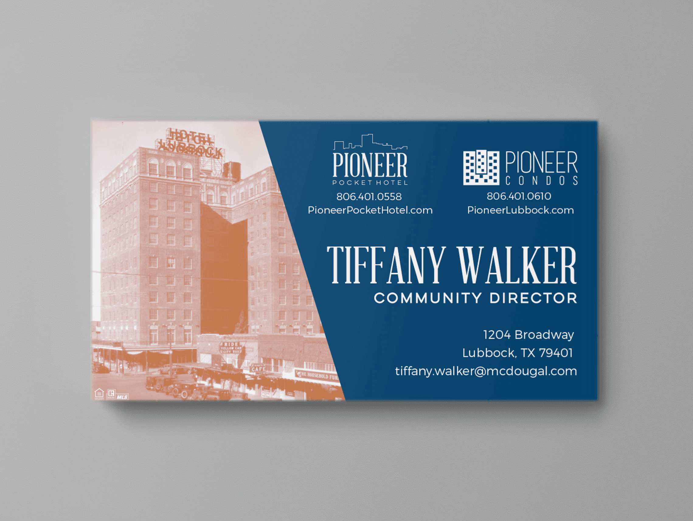 A business card mockup on a grey background.The business card is for the community director of the Pioneer Pcket Hotel and Pioneer Condos. The design features a duotone image of the building from the 1920s, and the contact info is on a blue background.