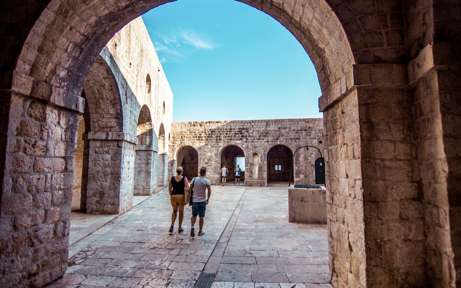 Vendégek sétálnak a kőívek alatt a Lovrijenac erődben, Dubrovnik.