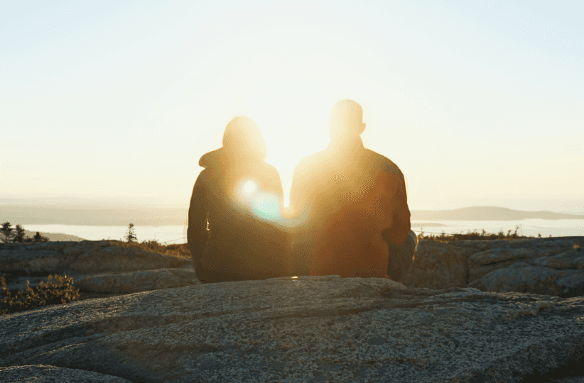 Photographie d'un couple devant un coucher de soleil