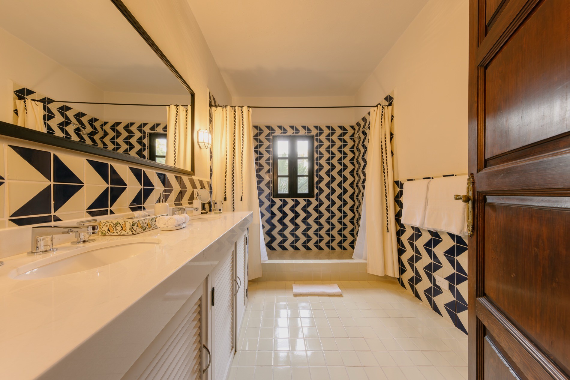 La Residencia bathroom with navy chevron tile, double vanity, and walk-in shower