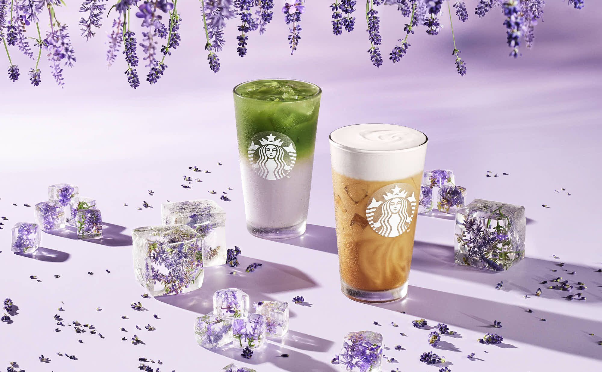 Two colorful drinks displayed on a lavender surface, surrounded by frosty elements.