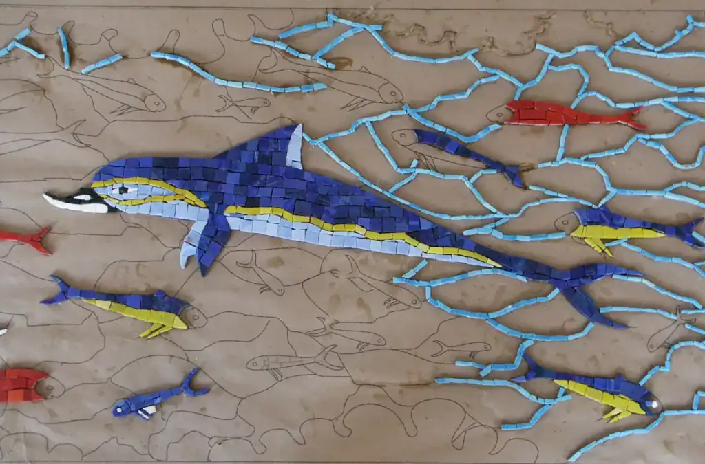 Mosaic shark with colorful tiles in an ocean scene.