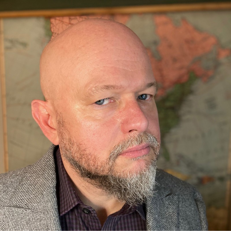 Image of Chuck Wyatt in a suit looking off to the sky