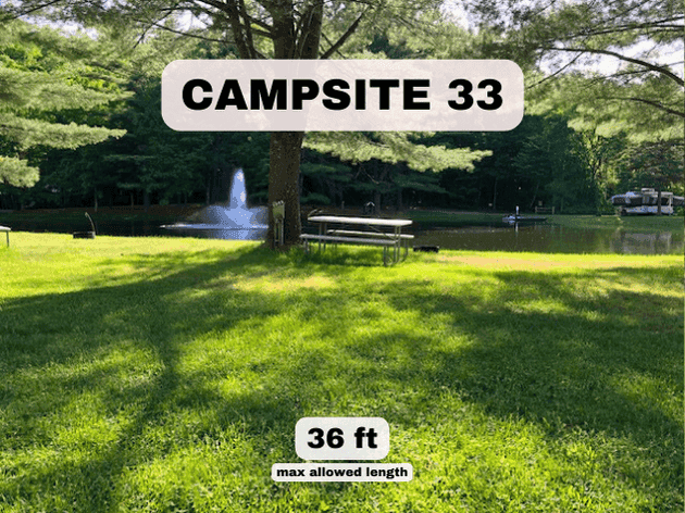 Campsite 33 at Pine Hollow Campground, a 36ft pondfront RV site with a fountain view, picnic table, and shaded lawn