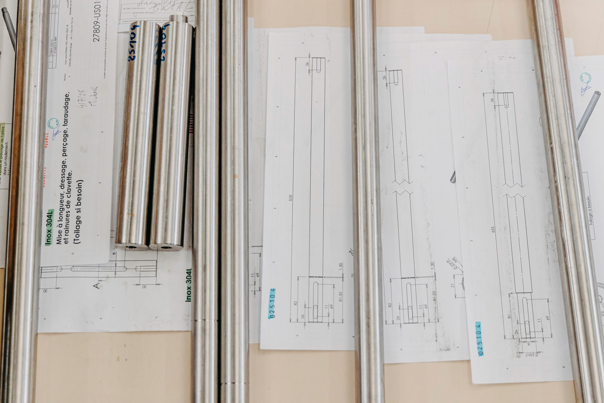 Plusieurs barres en inox posées su les plans de conception