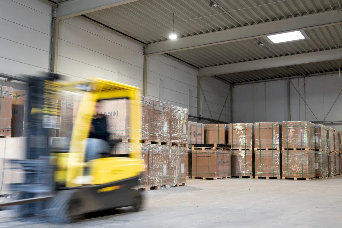 Gabelstapler transportiert Pakete in einem Lager mit gestapelter Ware.