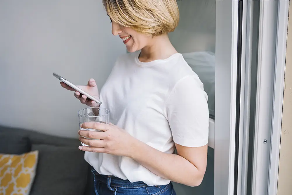 woman whith white shirt scrolls phone to lok on social media when she gets a quick break