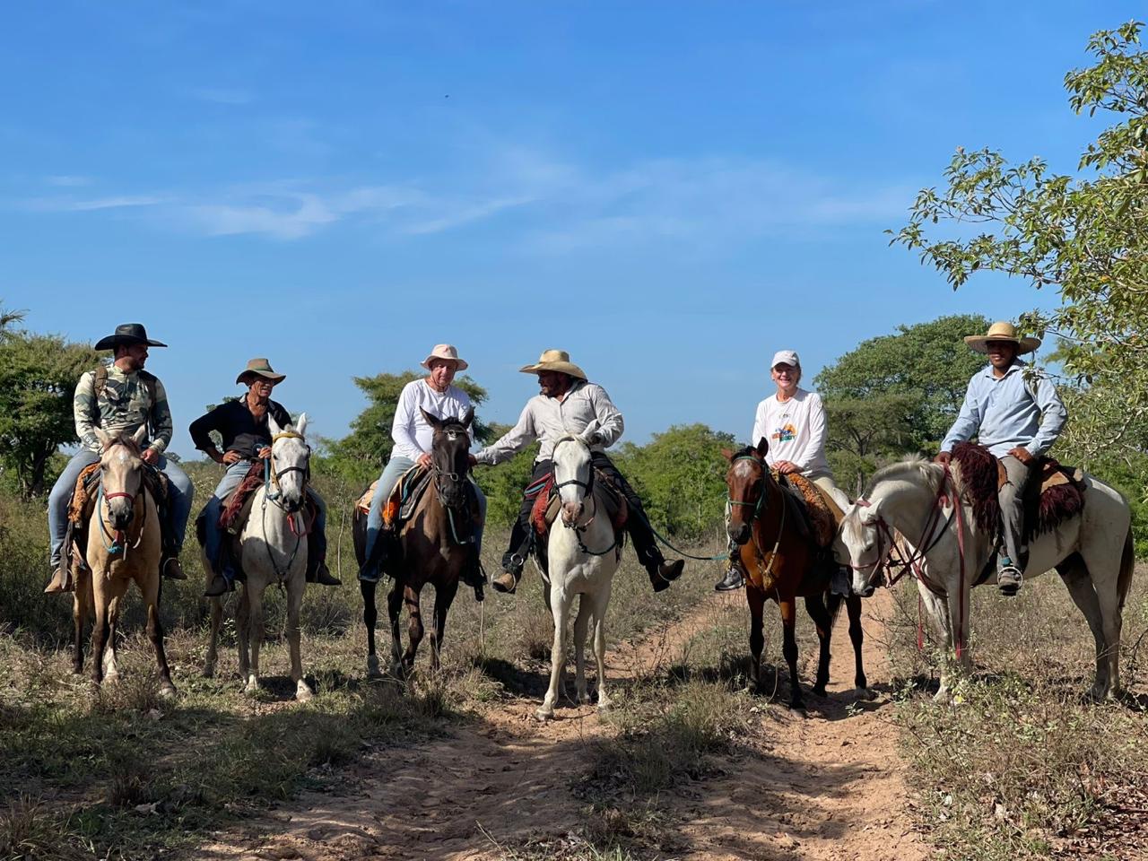 A mixed group of tourists and local pantaneiro cowboys on a horse riding day trip looking to the camera