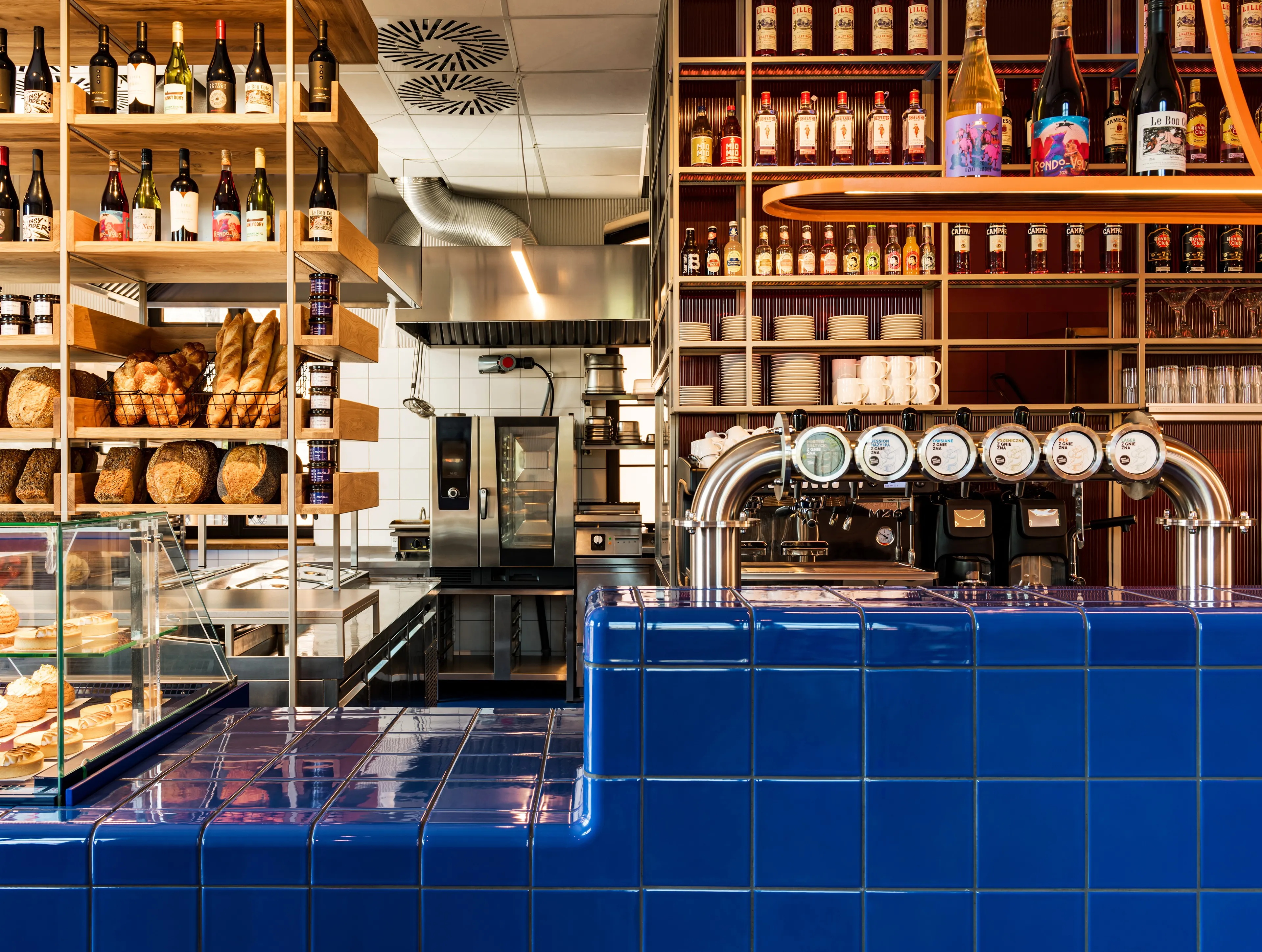 Woda bar counter with orange glass circle shelf, beer taps and pastry display, restaurant interior branding