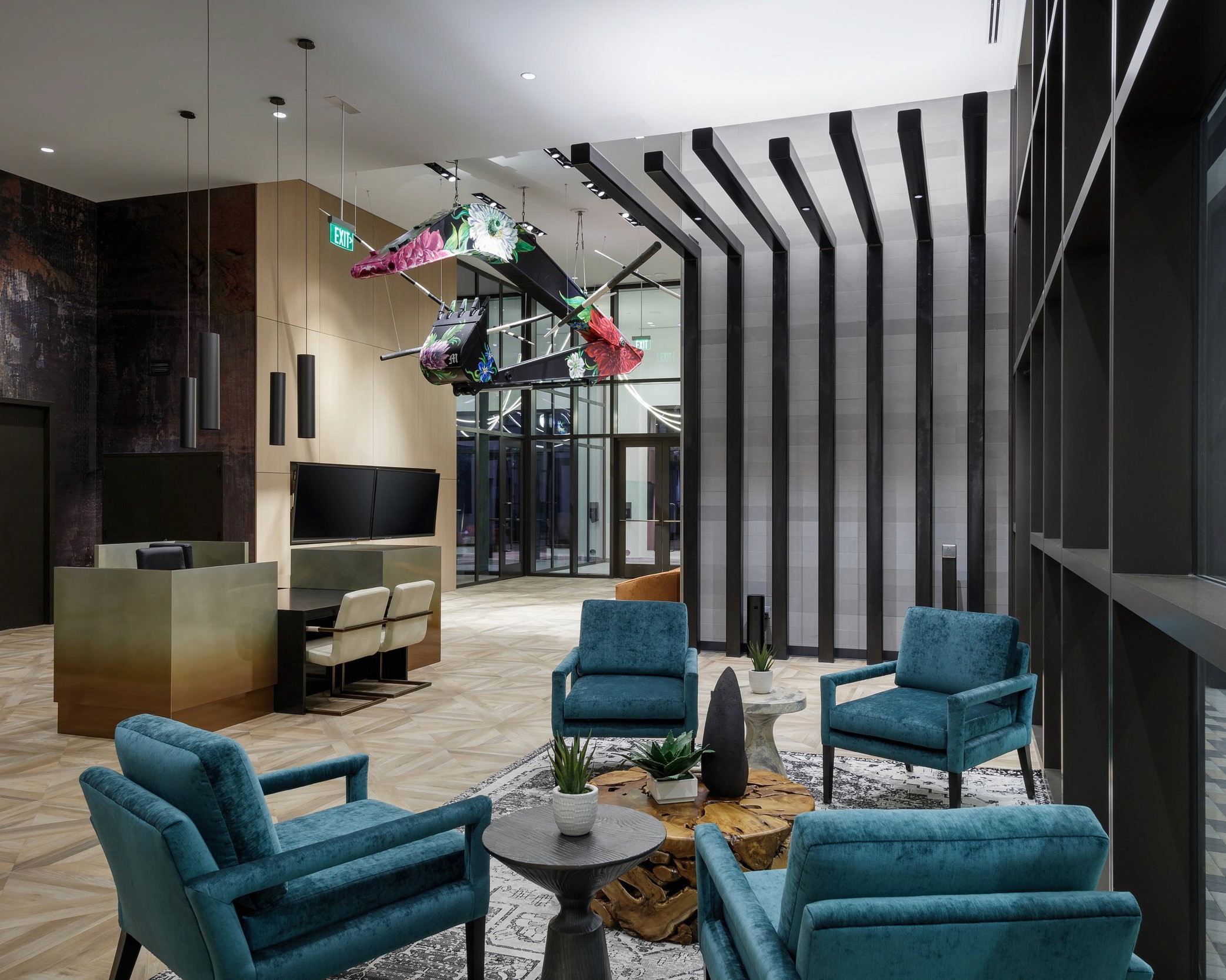 Modern lounge with teal chairs and abstract art.