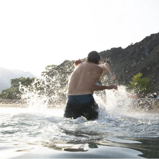 Person enjoying water sports and swimming in clear coastal waters near rocky cliffs