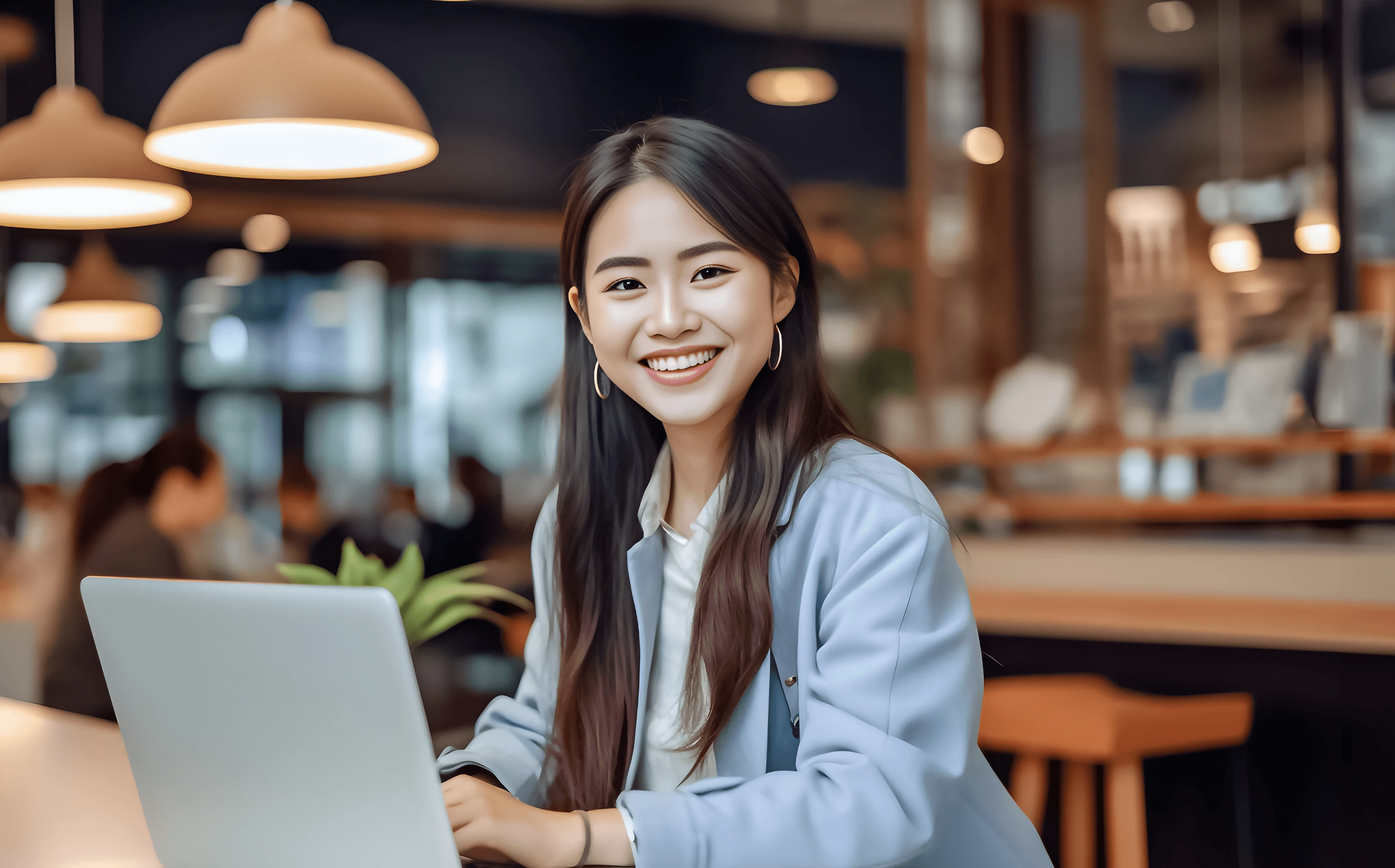 Headshot of Tiffany, a smiling young professional woman working on a laptop in a cafe.