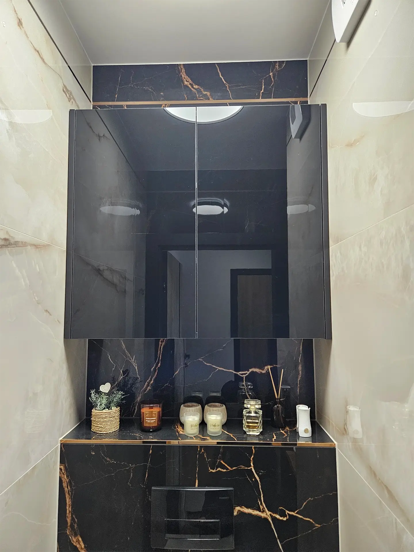 Nowoczesna zabudowa łazienkowa z podświetleniem na tle ciemnych, marmurowych płytek.