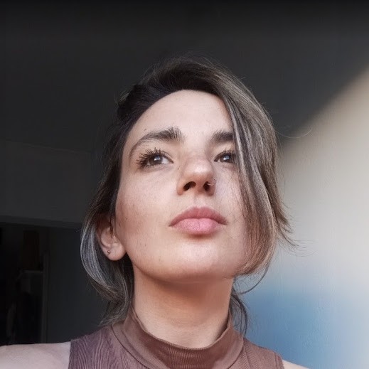 A thoughtful young person with dark hair gazes to the side, captured in soft black and white lighting.