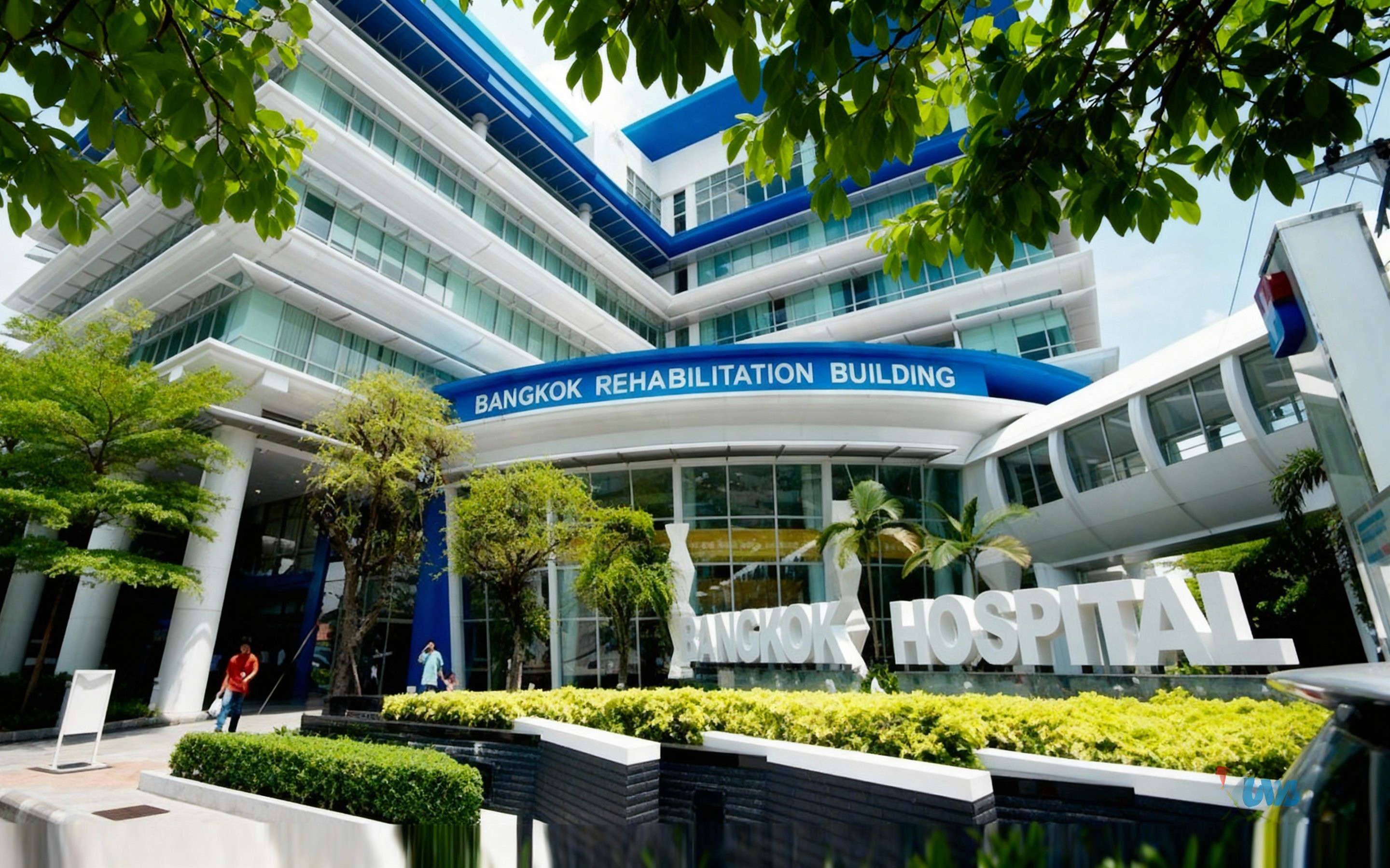 Modern exterior of Bangkok Hospital Chiang Mai’s rehabilitation building, featuring sleek glass architecture, blue and white signage, landscaped greenery, and people walking near the entrance.