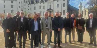 Groupe de professionnels de la transaction pharmaceutique posant devant un élégant bâtiment blanc.