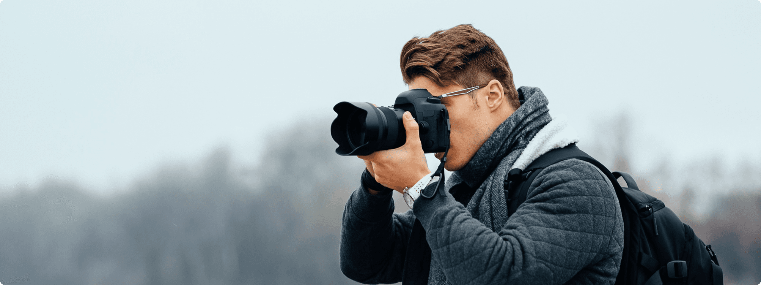 A man holding a camera, focused on taking a photo outdoors.