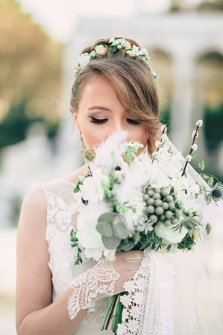 A bride in a lace wedding dress gently holds.