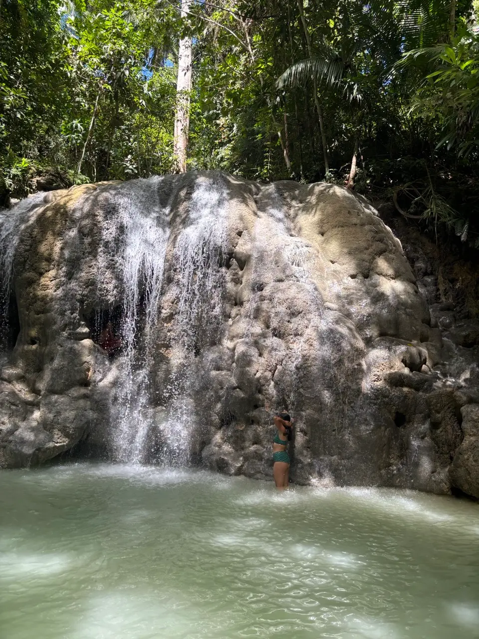 vrouw in bikini in water van een waterval