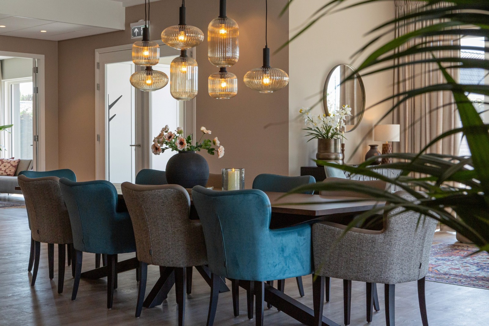 eettafel met blauwe en taupe stoelen en geribbelde glaslampen