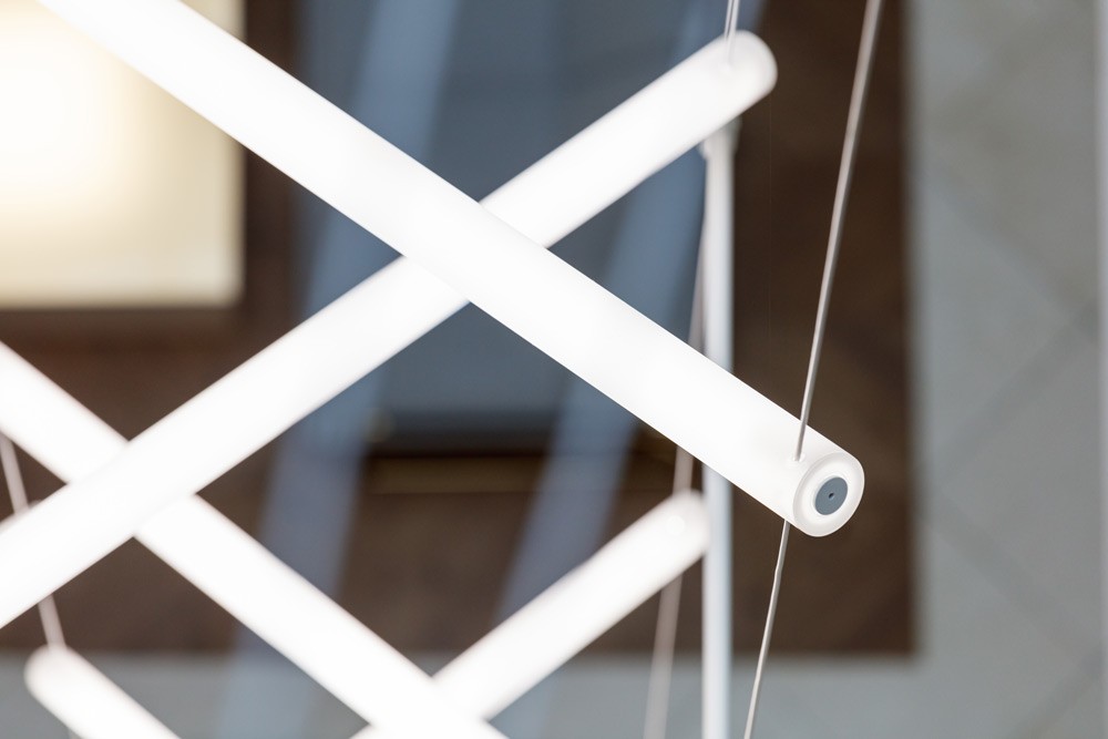 Close-up of custom acrylic LED light units suspended on tensioned steel cables