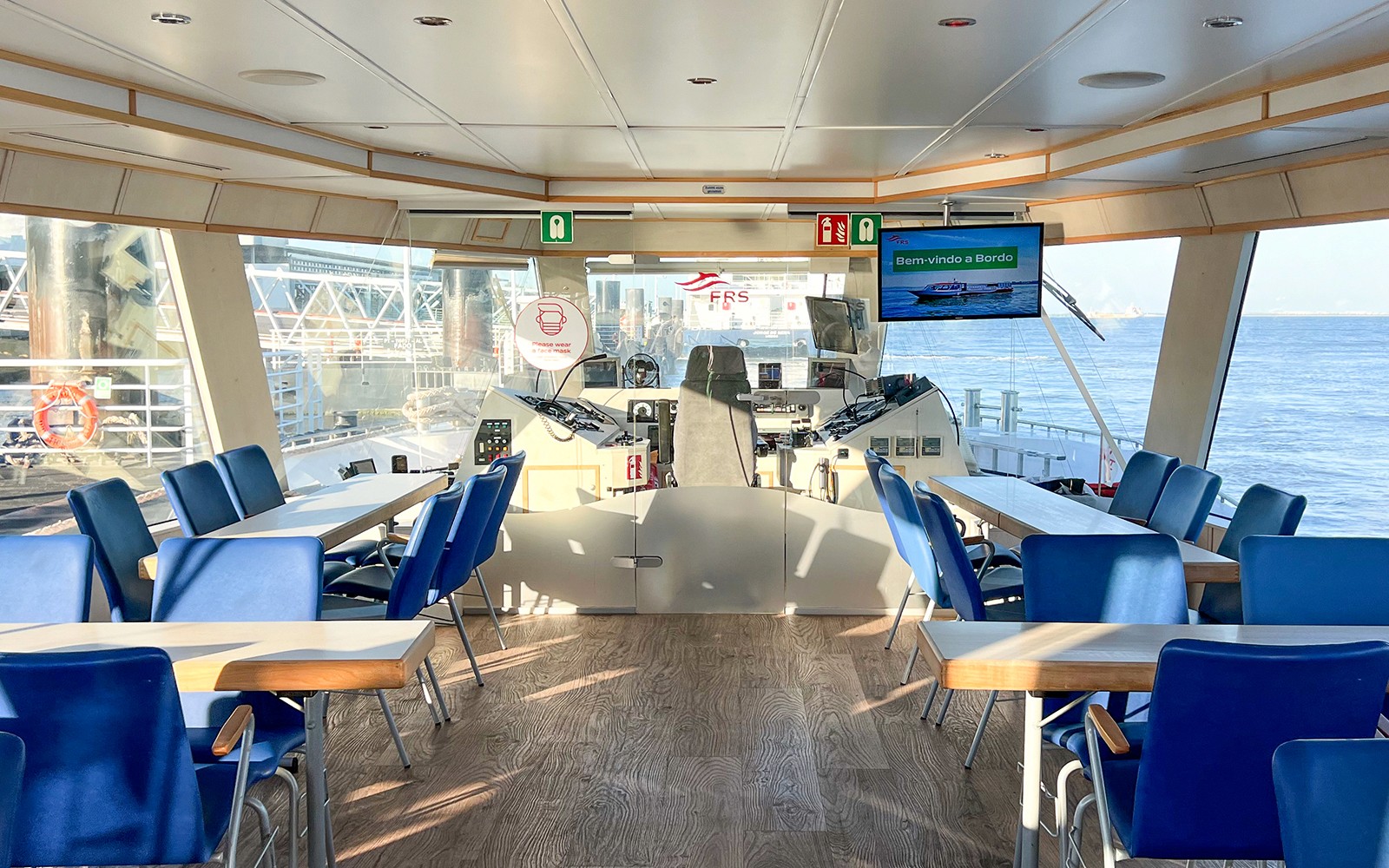 Interior of a boat cruise on the Tagus River with seating and navigation controls.