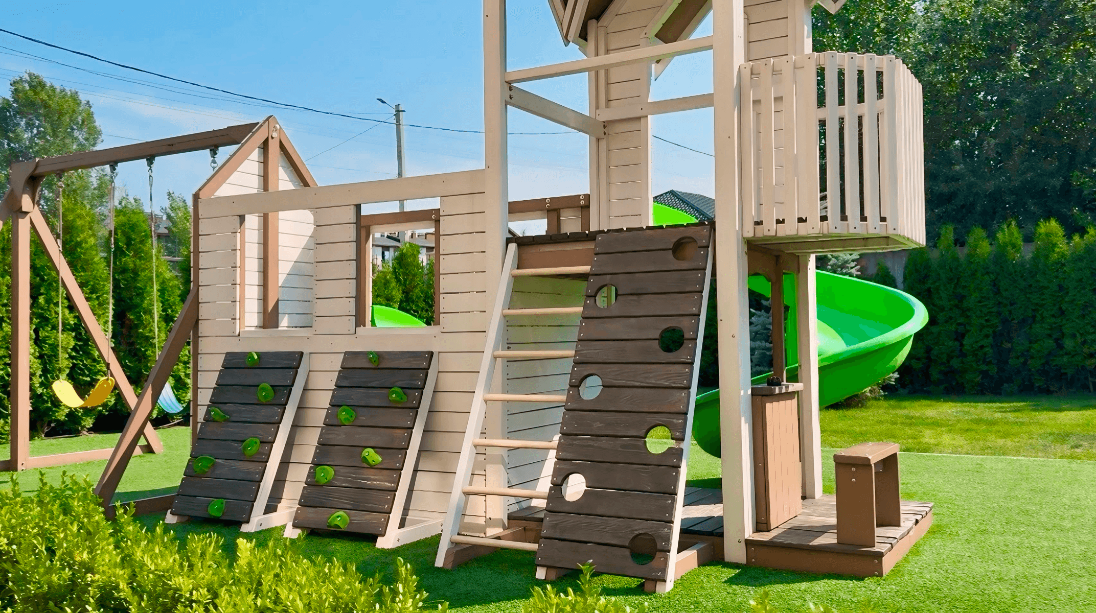 Боковий ракурс дитячого майданчика з гіркою, скеледромом і гойдалками