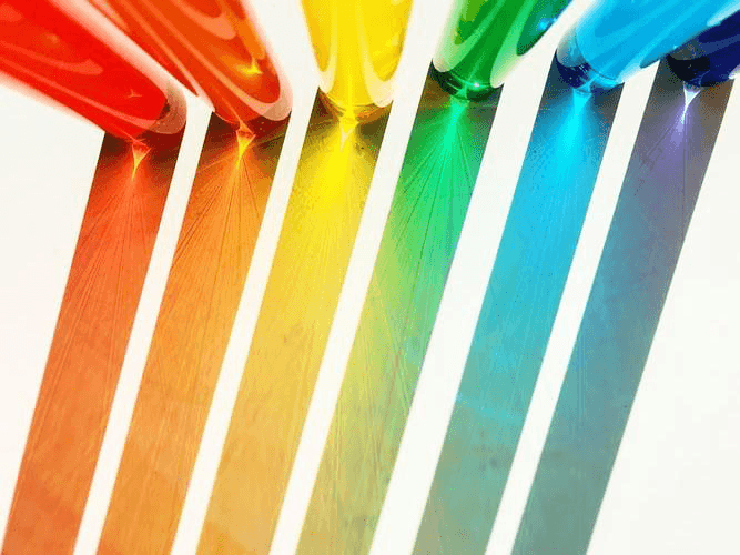 Some colorful fabric with bright, shiny brushes against a wall.