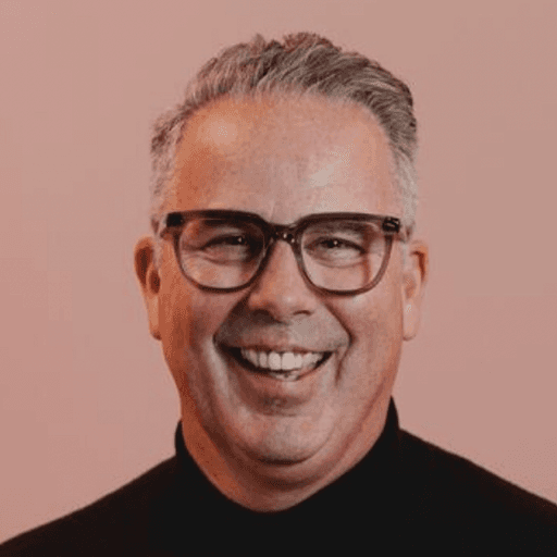 A woman with straight blonde hair wearing a light colored sweater looks away.