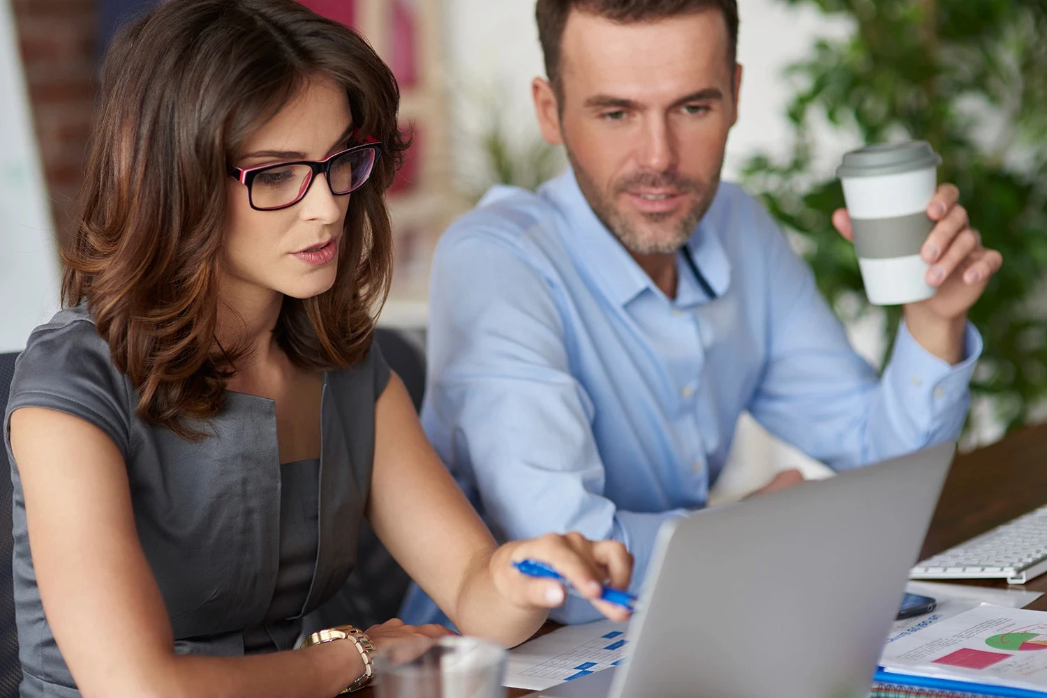 Digital marketing specialists discussing insights while reviewing data on a computer.